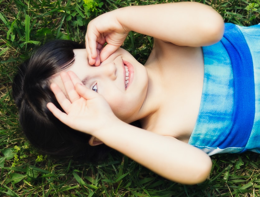 Child lying in grass smiling upward